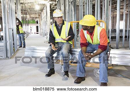 Stock Photography - Construction workers talking at construction site. Fotosearch