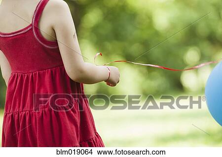 Picture - Girl with balloon tied to wrist outdoors. Fotosearch