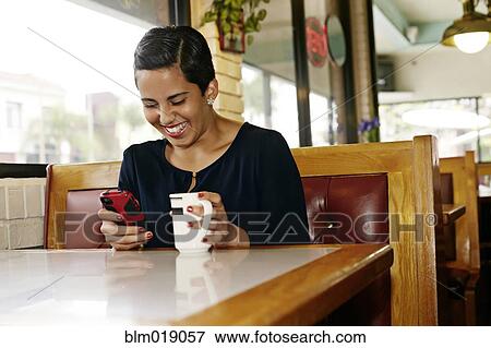 Hispanic businesswoman using cell phone in restaurant View Large Photo Image Stock Photo - Hispanic businesswoman using cell phone in restaurant. Fotosearch