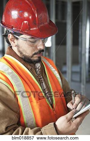 Stock Photo - Hispanic construction worker making notes. Fotosearch