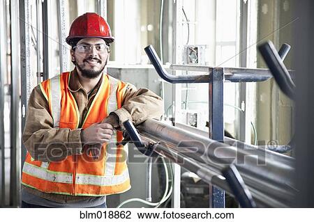 Hispanic construction worker smiling at construction site View Large Photo Image Stock Image - Hispanic construction worker smiling at construction site. Fotosearch