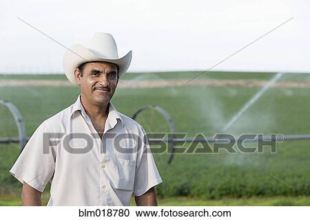 Stock Image - Hispanic farmer standing on farm. Fotosearch