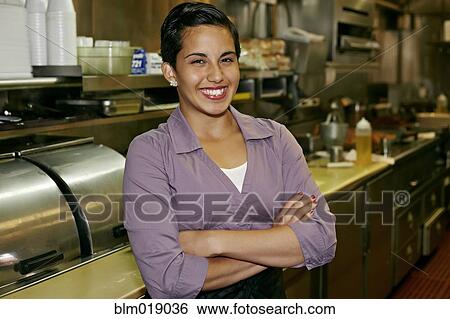 Stock Photograph - Hispanic waitress smiling in restaurant. Fotosearch