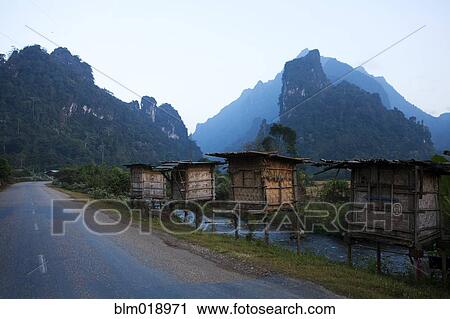 Stock Image - Huts on rural road, Vang Vieng, Vang Vieng, Laos. Fotosearch
