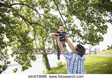 Stock Photograph - Japanese father playing with son in park. Fotosearch
