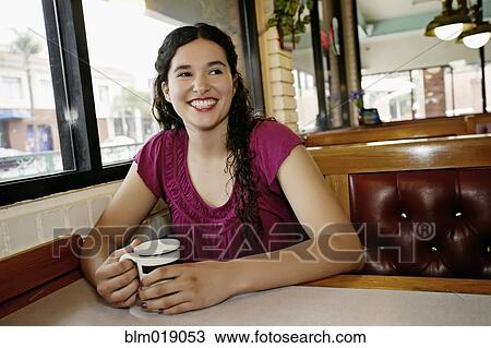 Stock Image - Mixed race woman having coffee in restaurant. Fotosearch