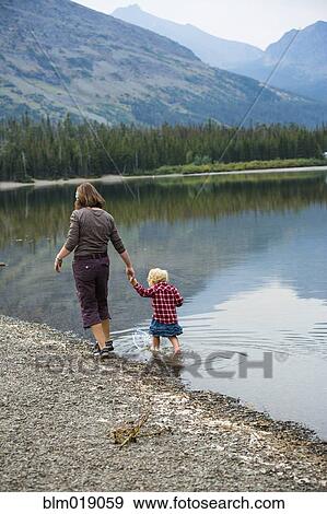 Stock Photo - Mother and child walking in still rural lake. Fotosearch