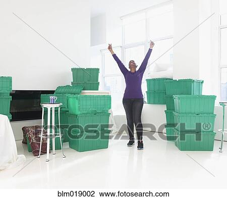 Stock Image - Older Black woman cheering in new home. Fotosearch