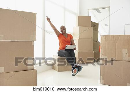Stock Image - Older Black woman cheering in new home. Fotosearch