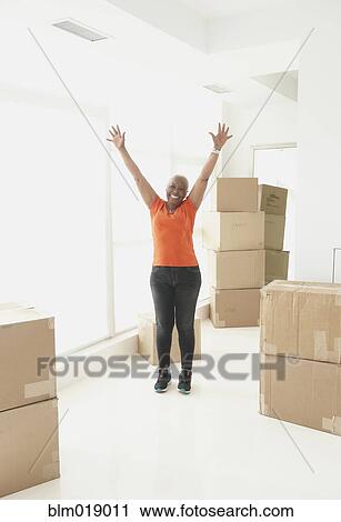 Stock Image - Older Black woman cheering in new home. Fotosearch