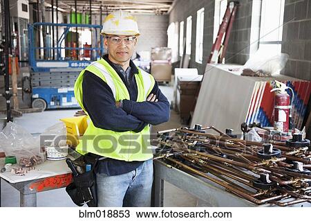 Stock Image - Pacific Islander construction worker with arms crossed. Fotosearch