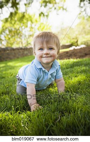 Stock Photo - Smiling boy crawling on grass. Fotosearch