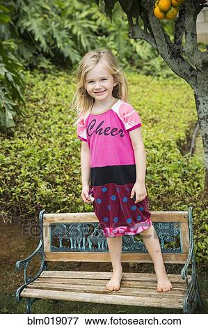Stock Photo - Smiling girl standing on park bench. Fotosearch