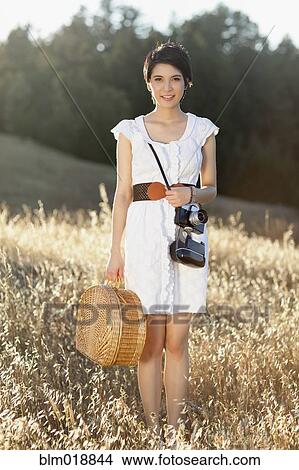 Picture - Thai woman carrying picnic basket in grass. Fotosearch