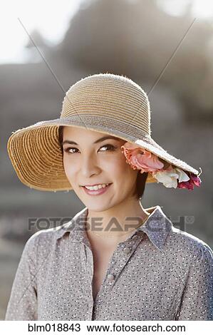 Stock Image - Thai woman wearing sun hat outdoors. Fotosearch