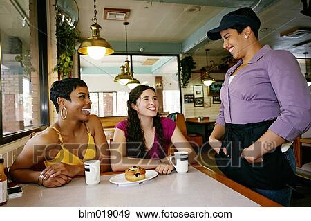 Stock Photo - Waitress talking to customers in restaurant. Fotosearch