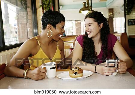 Stock Image - Women having coffee together in restaurant. Fotosearch