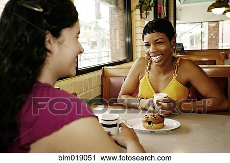 Stock Image - Women having coffee together in restaurant. Fotosearch
