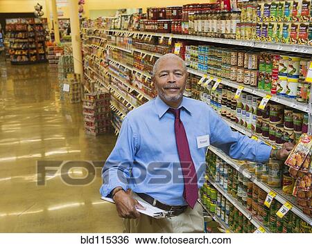 Stock Photograph - African American businessman smiling in grocery store. Fotosearch