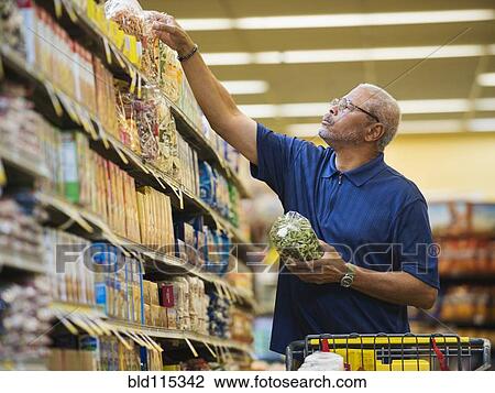 Stock Image - African American man shopping in grocery store. Fotosearch