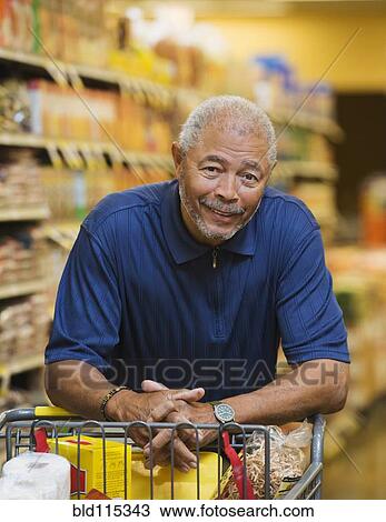 Stock Image - African American man smiling in grocery store. Fotosearch