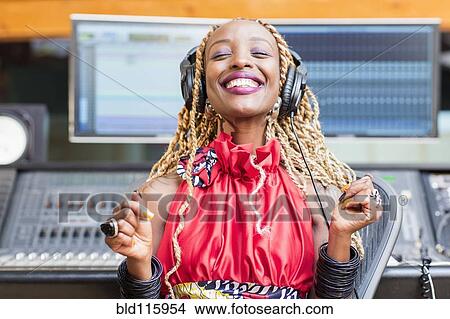 Picture - African American singer listening to track in studio. Fotosearch