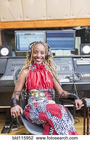 Stock Image - African American singer listening to track in studio. Fotosearch