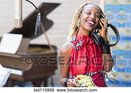 Stock Photograph - African American singer listening to track in studio. Fotosearch