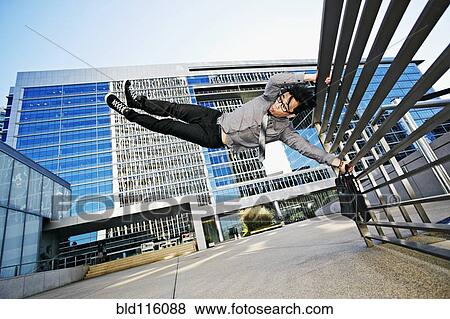 Stock Photo - Asian businessman doing tricks on handrail. Fotosearch
