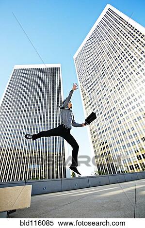 Asian businessman leaping on urban rooftop View Large Photo Image Stock Photography - Asian businessman leaping on urban rooftop. Fotosearch
