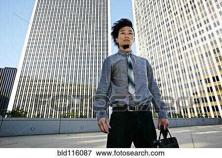Stock Photo - Asian businessman on urban rooftop. Fotosearch