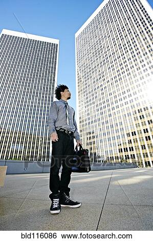 Stock Photograph - Asian businessman on urban rooftop. Fotosearch