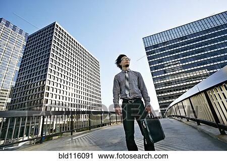 Stock Image - Asian businessman on urban walkway. Fotosearch