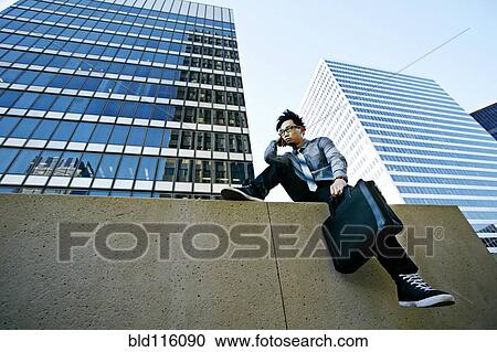 Asian businessman sitting on ledge in city View Large Photo Image Stock Image - Asian businessman sitting on ledge in city. Fotosearch
