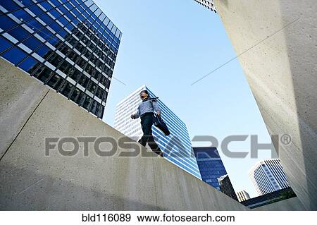 Asian businessman walking on ledge in city View Large Photo Image Stock Photo - Asian businessman walking on ledge in city. Fotosearch