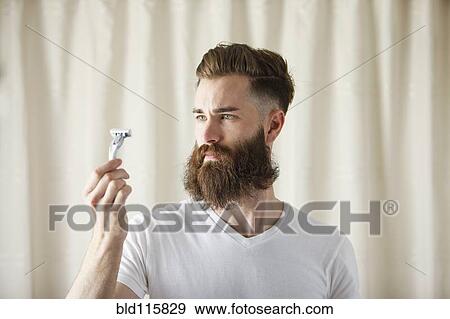 Bearded Caucasian man examining razor View Large Photo Image Stock Photo - Bearded Caucasian man examining razor. Fotosearch