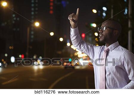 Stock Photograph - Black businessman hailing taxi on city street. Fotosearch