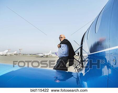 Stock Image - Black businessman leaving airplane on runway. Fotosearch