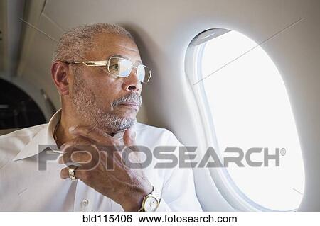 Stock Photograph - Black businessman looking out airplane window. Fotosearch