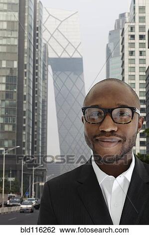 Stock Image - Black businessman smiling on city street. Fotosearch