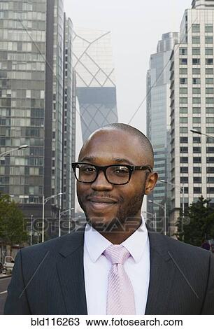 Stock Image - Black businessman smiling on city street. Fotosearch