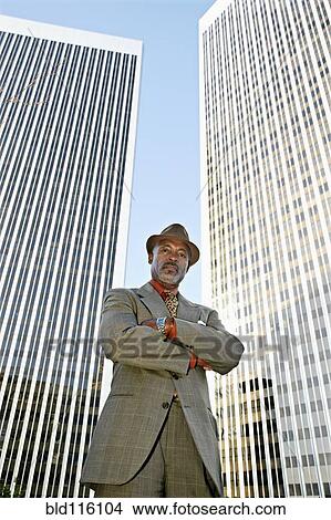 Black businessman standing in front of highrises View Large Photo Image Picture - Black businessman standing in front of highrises. Fotosearch