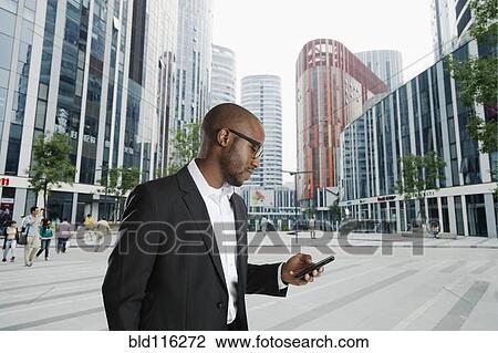 Black businessman using cell phone on city street, Beijing, Beijing, China View Large Photo Image Stock Image - Black businessman using cell phone on city street, Beijing, Beijing, China. Fotosearch