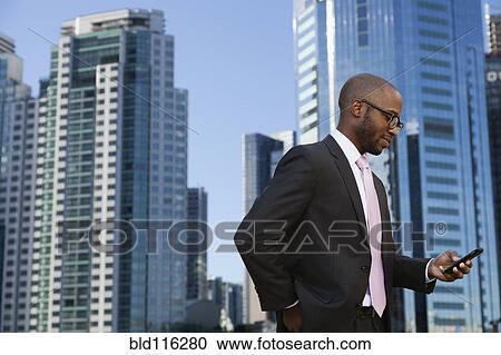 Black businessman using cell phone on city street View Large Photo Image Stock Image - Black businessman using cell phone on city street. Fotosearch
