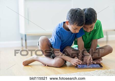 Boys using digital tablet on floor View Large Photo Image Stock Image - Boys using digital tablet on floor. Fotosearch