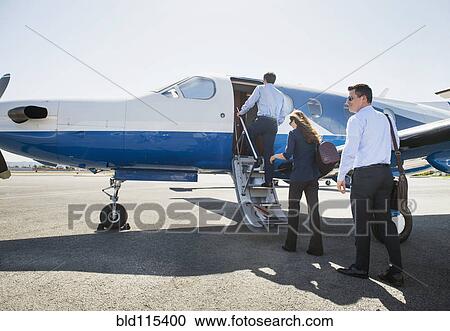 Stock Image - Business people boarding airplane on runway. Fotosearch