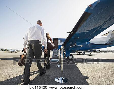 Stock Image - Business people boarding airplane on runway. Fotosearch