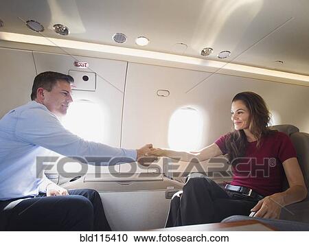 Stock Image - Business people shaking hands on airplane. Fotosearch