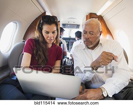 Picture - Business people using laptop on airplane. Fotosearch