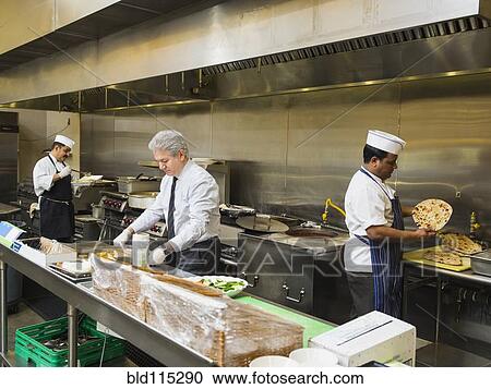 Stock Image - Businessman and chefs working in kitchen. Fotosearch